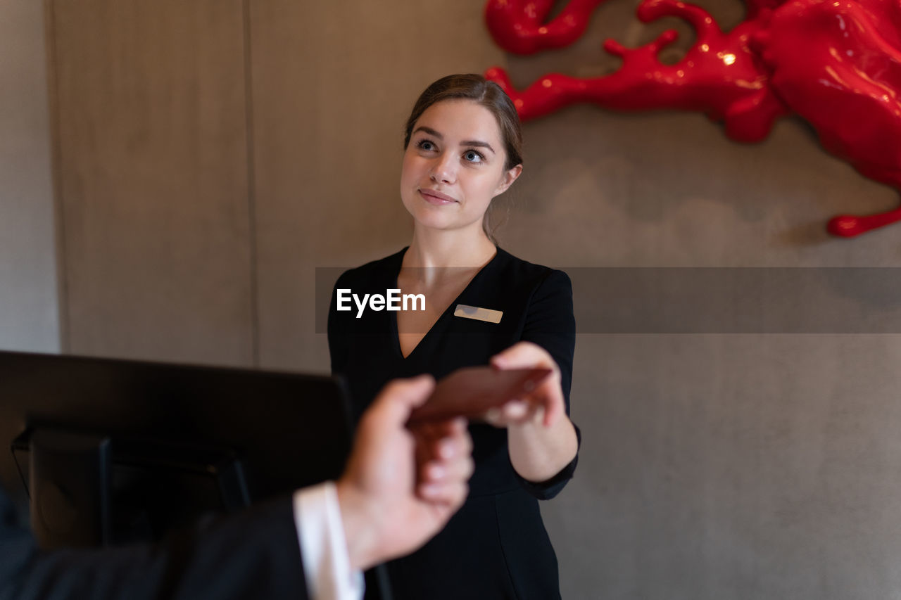Female receptionist receiving room key from businessman before departing from hotel