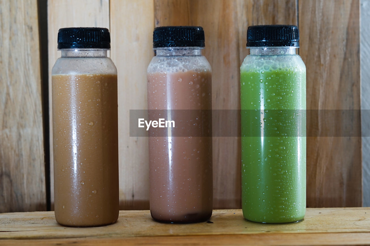 food and drink, food, bottle, healthy eating, drink, refreshment, wood, container, wellbeing, juice, indoors, freshness, no people, soft drink, smoothie, produce, vegetable, studio shot, close-up, still life, table, household equipment, in a row, variation