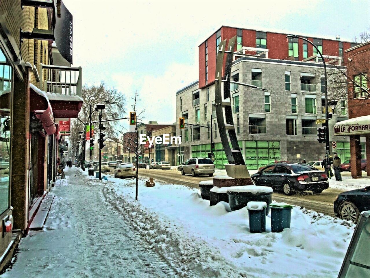 Snowy city street against sky