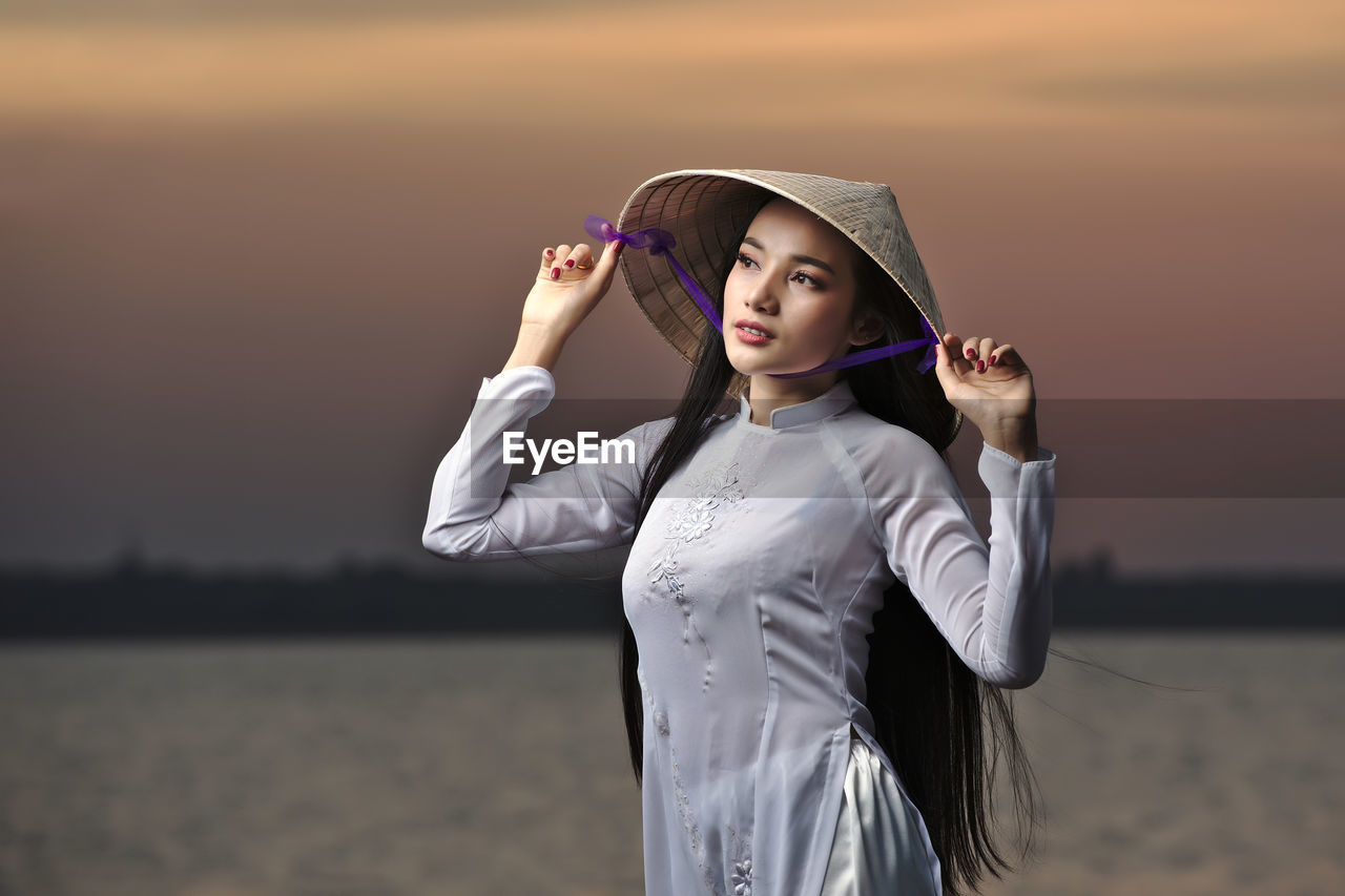 Portrait of beautiful asian girls with ao dai vietnam traditional dress on sunset landscapes.