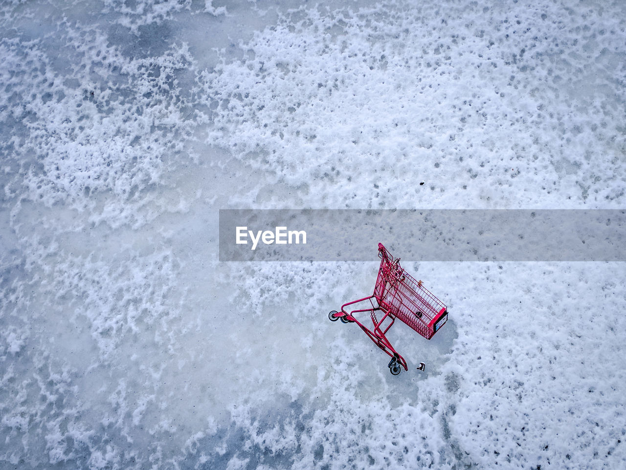 High angle view of red shopping cart on frozen water.