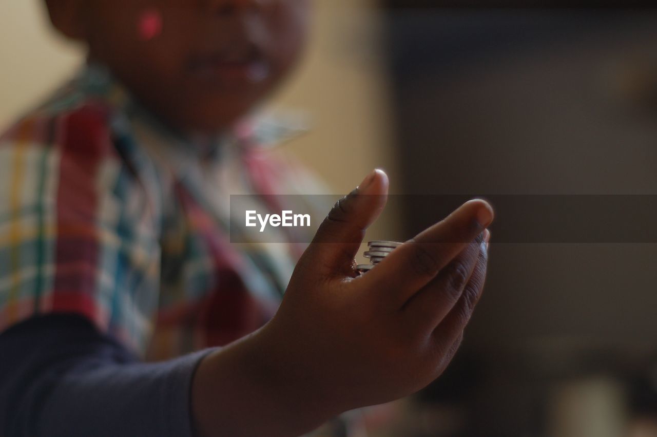 Midsection of boy holding coins at home