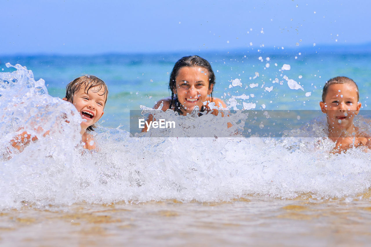 Portrait of happy woman and boys in sea