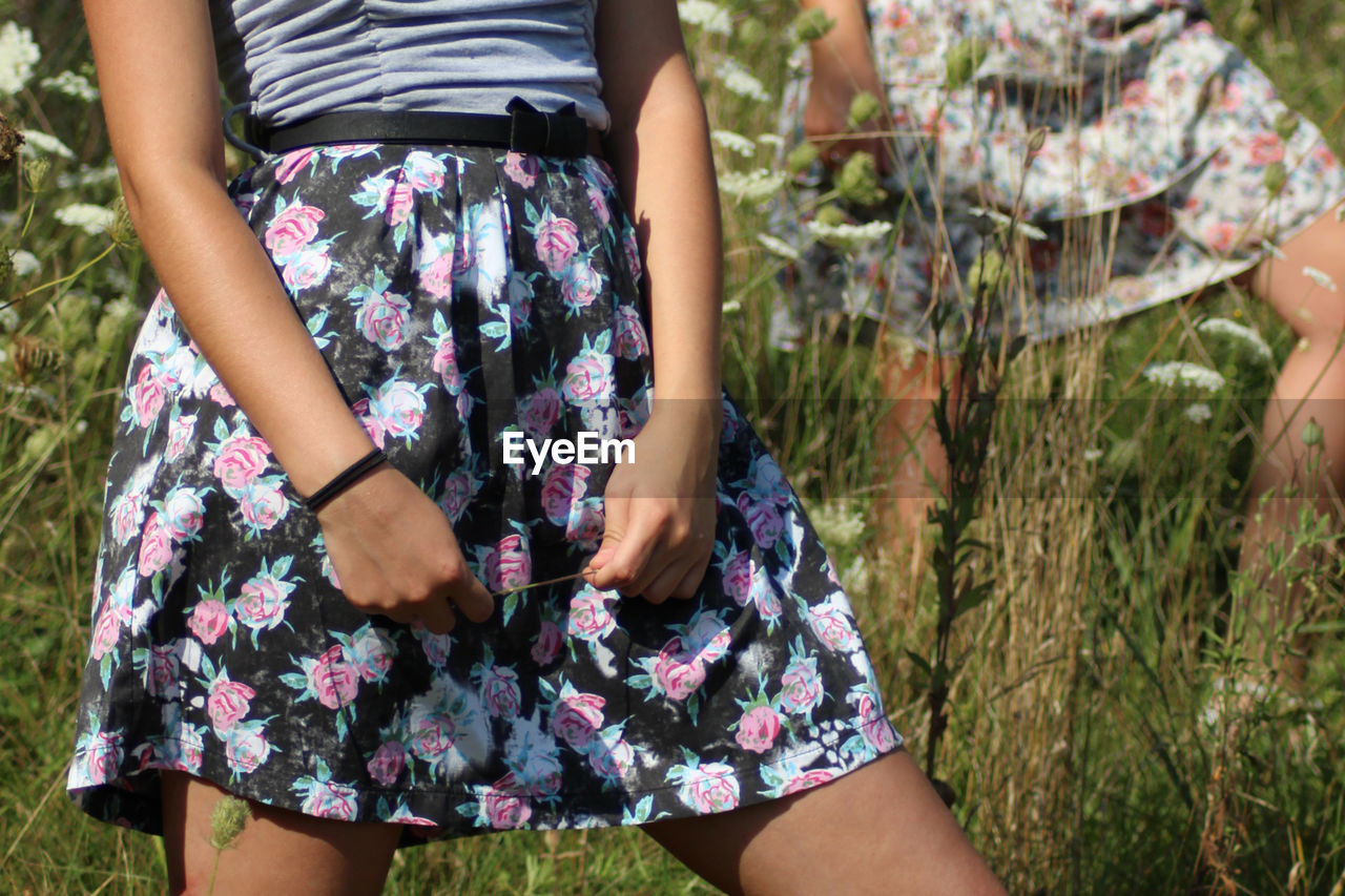 Midsection of woman wearing floral patterned skirt while standing on land