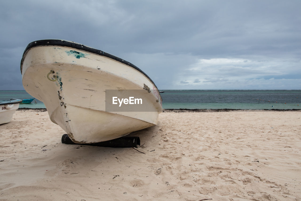 Abandoned boat on beach against sky