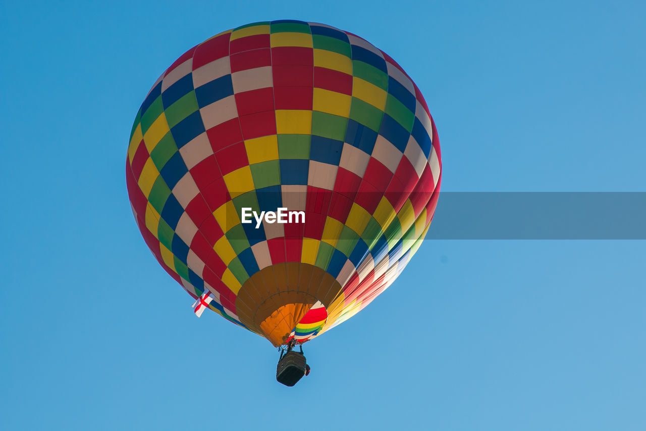 Low angle view of colorful hot air balloon flying against clear blue sky