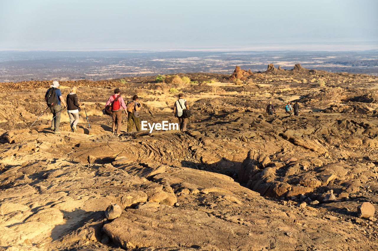 Rear view of people hiking on mountain against sky