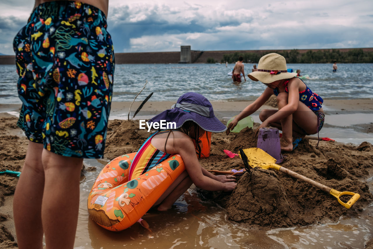 Low level photo of young children digging in sand at beach