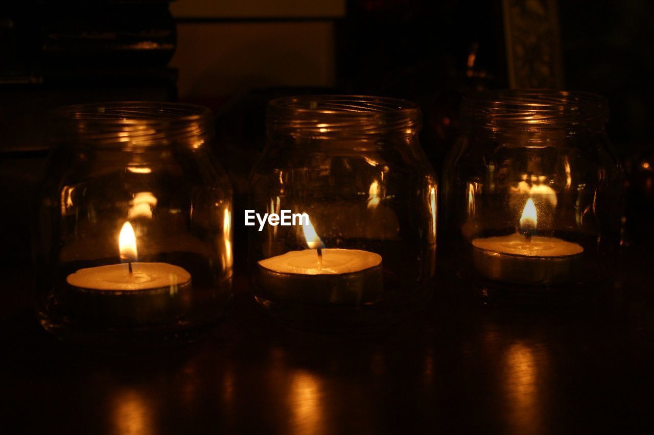 CLOSE-UP OF LIT TEA LIGHT CANDLES IN ROOM