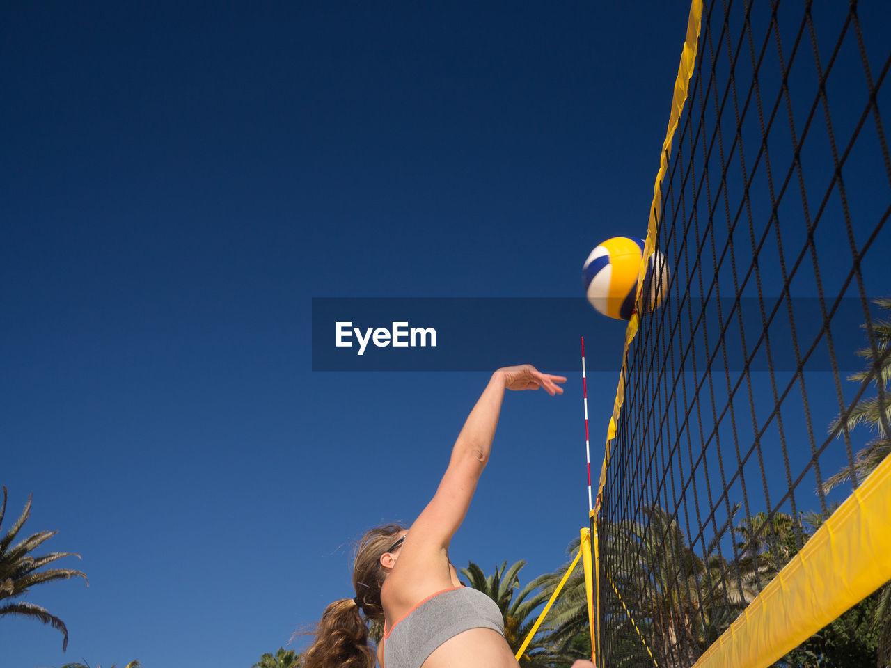 Woman playing volleyball at beach against sky