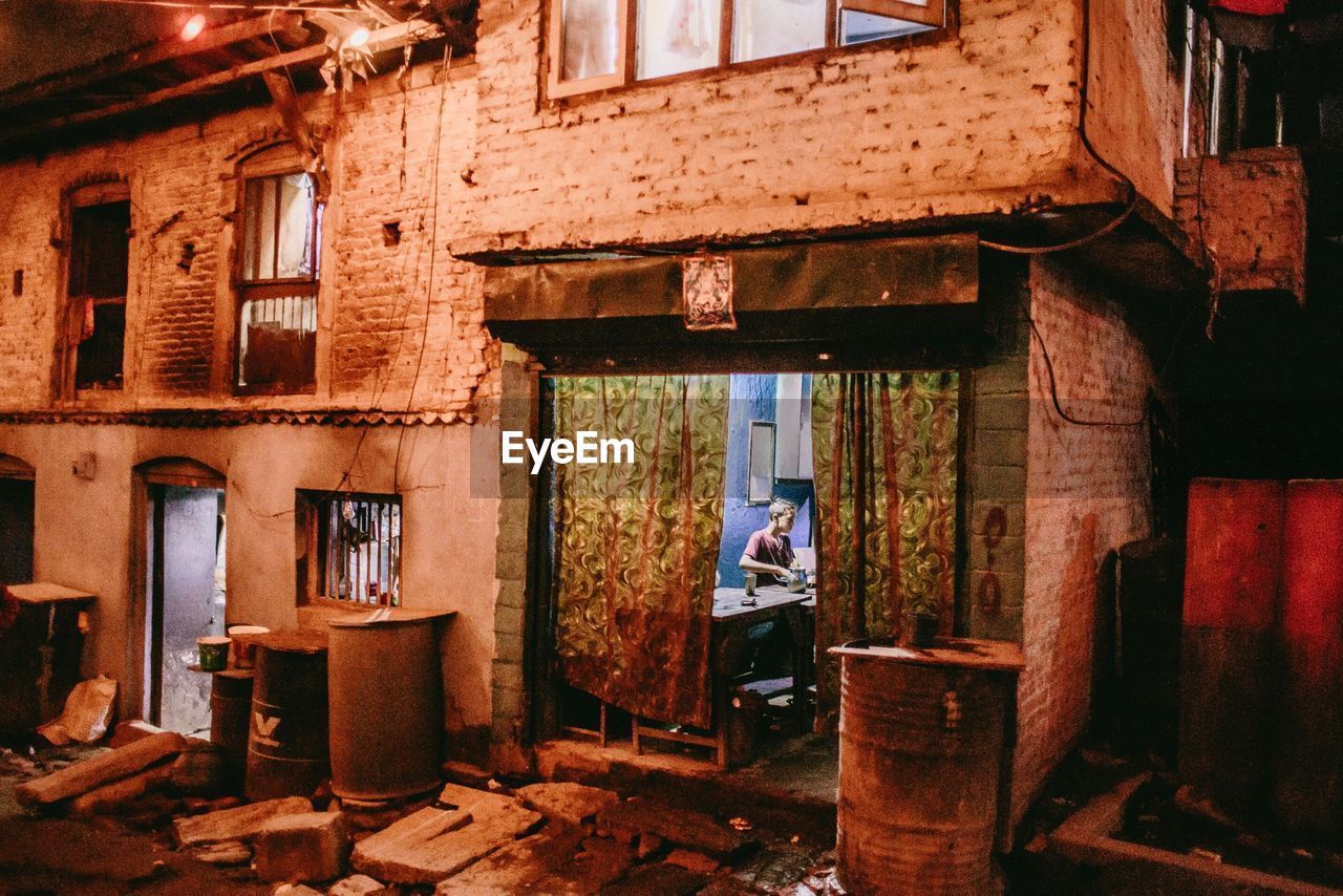 MAN STANDING ON WINDOW OF ABANDONED HOUSE