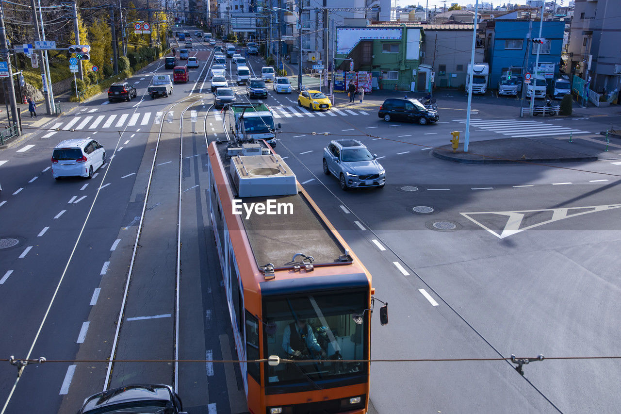transportation, mode of transportation, motor vehicle, car, road, city, lane, street, architecture, land vehicle, traffic, sign, city street, symbol, metropolitan area, high angle view, road marking, city life, marking, bus, building exterior, built structure, vehicle, day, transport, infrastructure, motion, travel, highway, on the move, nature, outdoors, no people, cityscape, public transportation, travel destinations