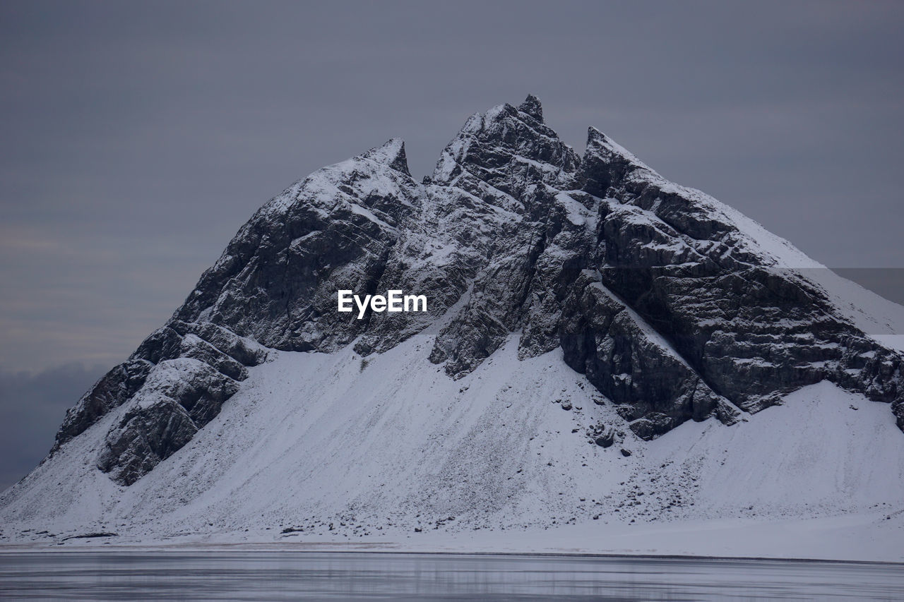 FROZEN LAKE AGAINST MOUNTAIN DURING WINTER