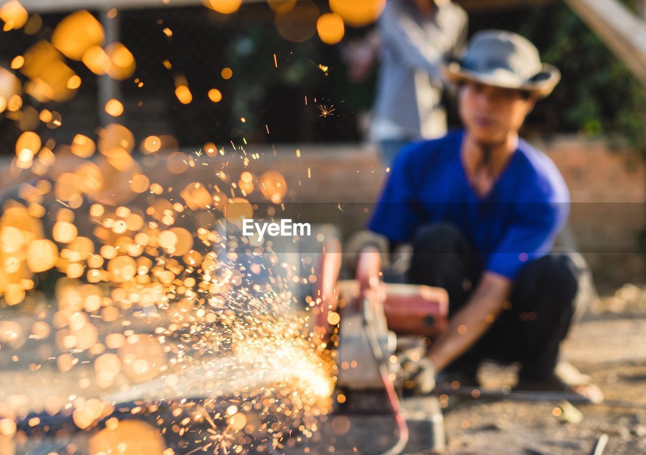 Sparks emitting from metal against worker working at construction site