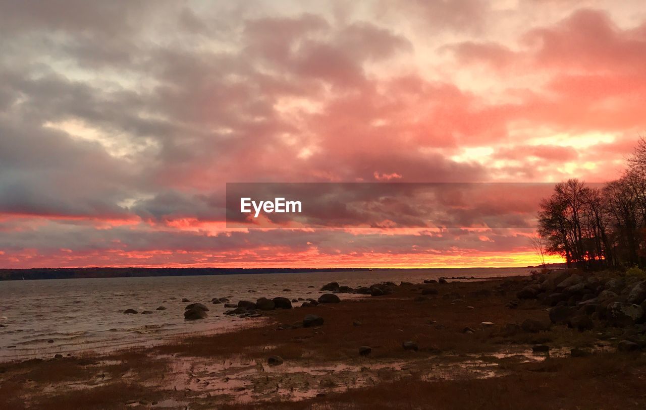 View of calm sea against cloudy sky during sunset