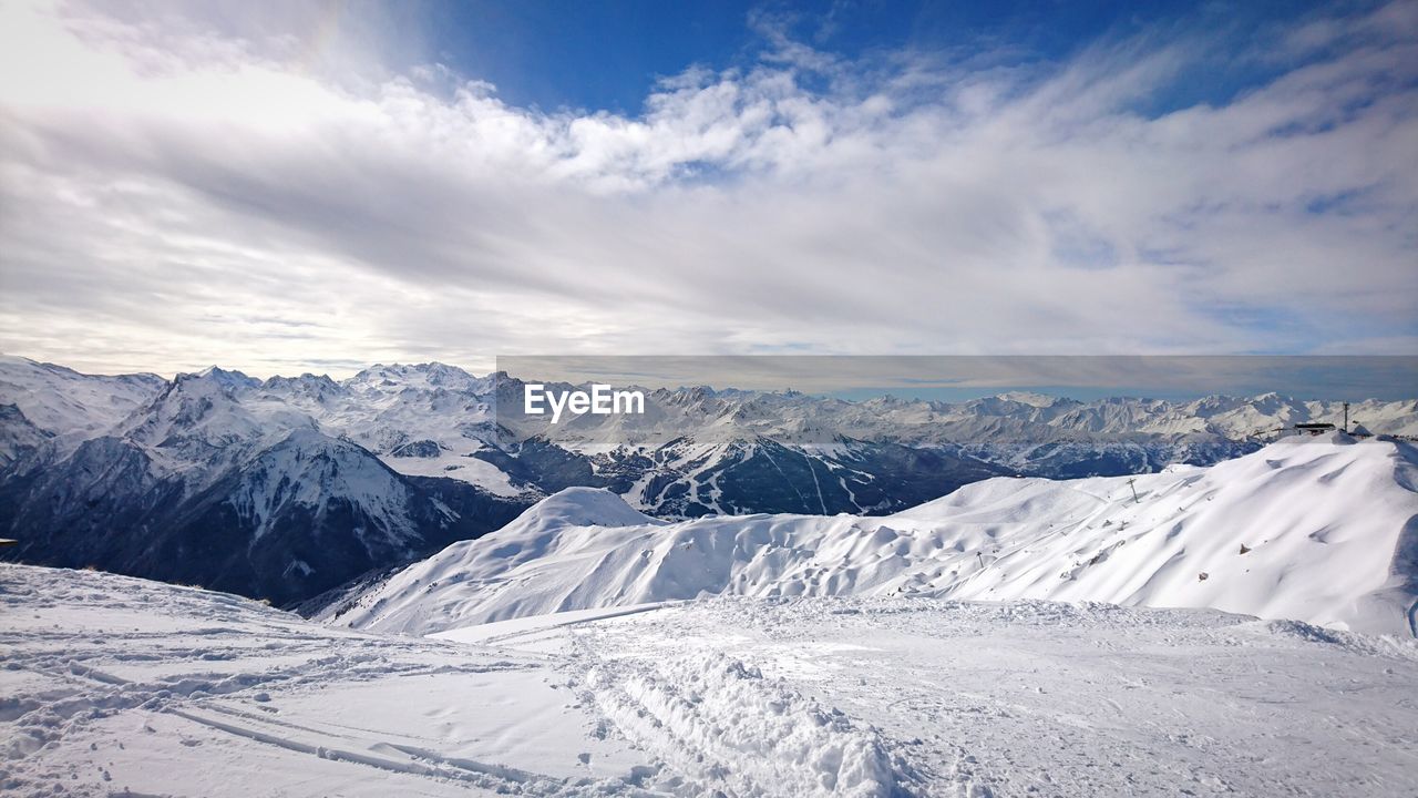 Snow covered mountains against cloudy sky