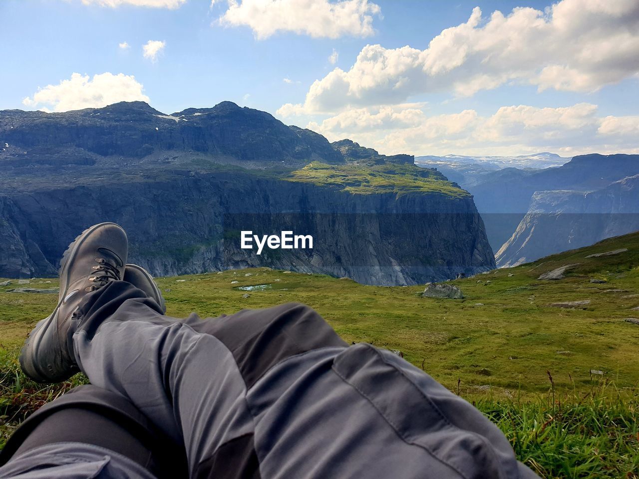 Low section of man lying on mountain against sky