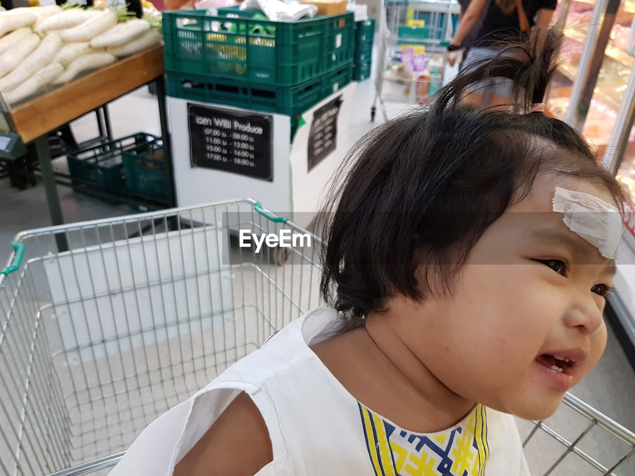 Close-up of cute girl sitting on shopping cart in supermarket