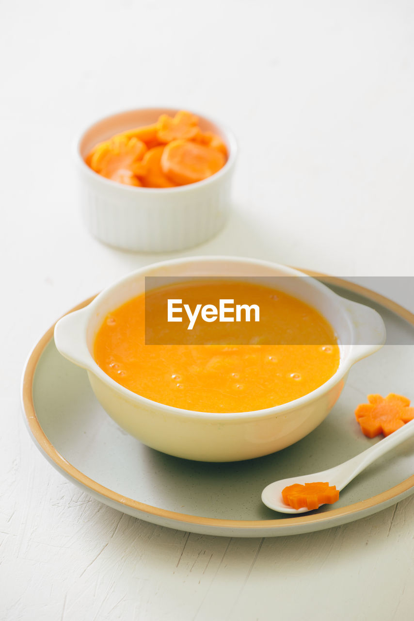 Carrot baby puree in bowl isolated on light background