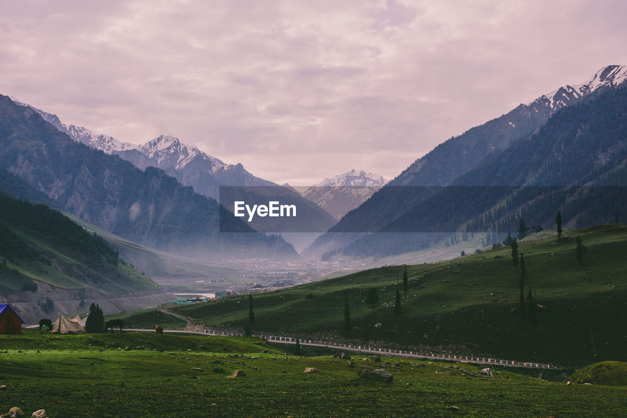 Scenic view of agricultural field by mountains against sky