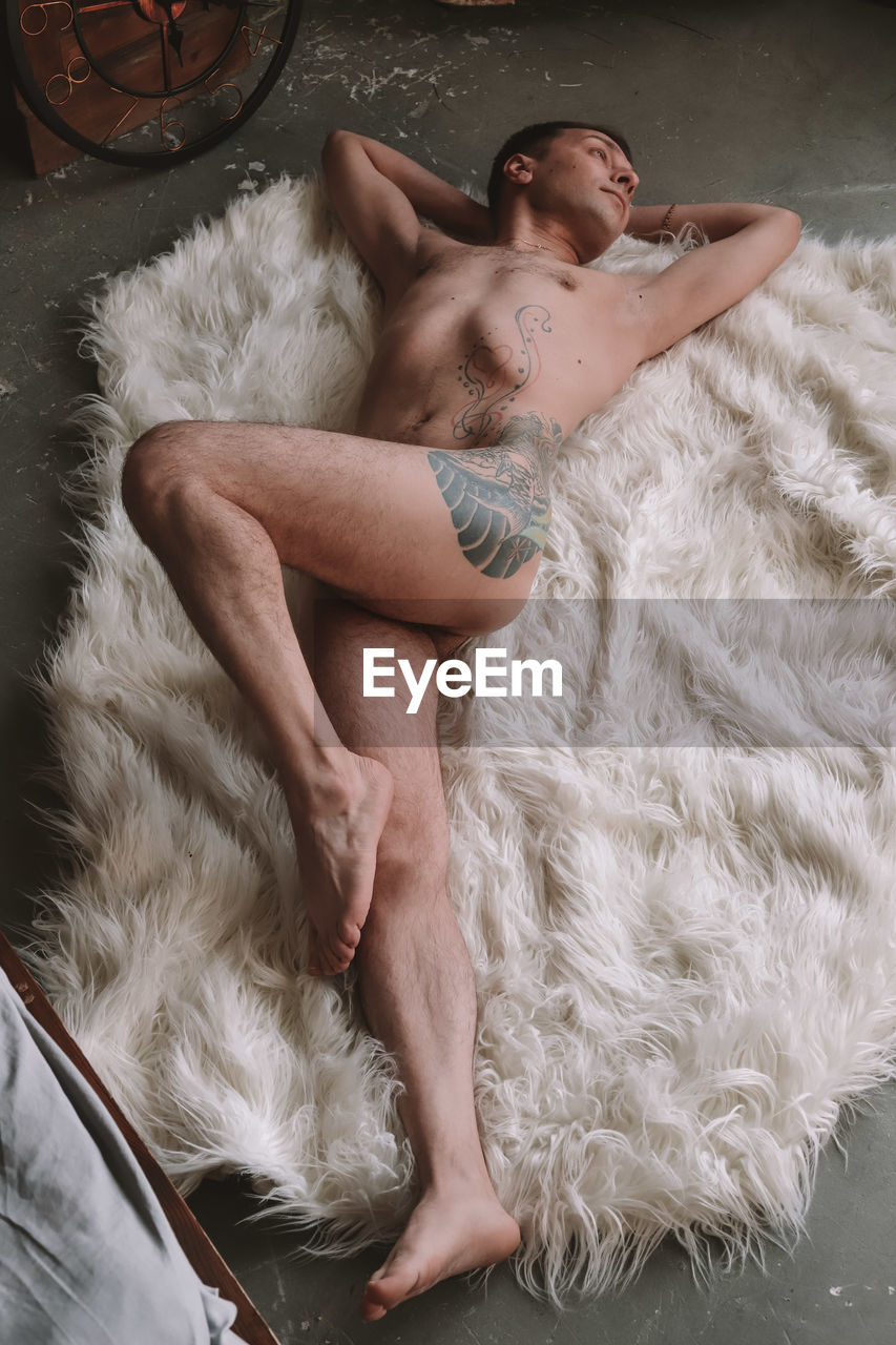 Full length of naked man lying down on fur