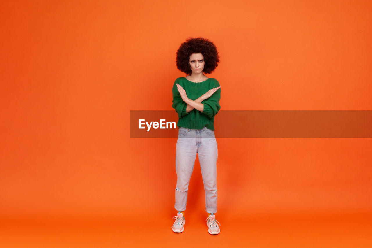 Full length portrait of woman gesturing against colored background