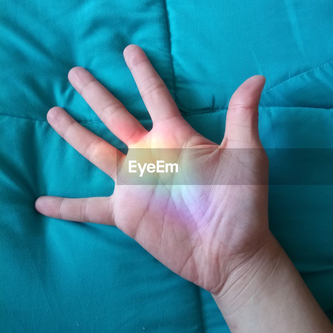 Close-up of human hand with spectrum on duvet