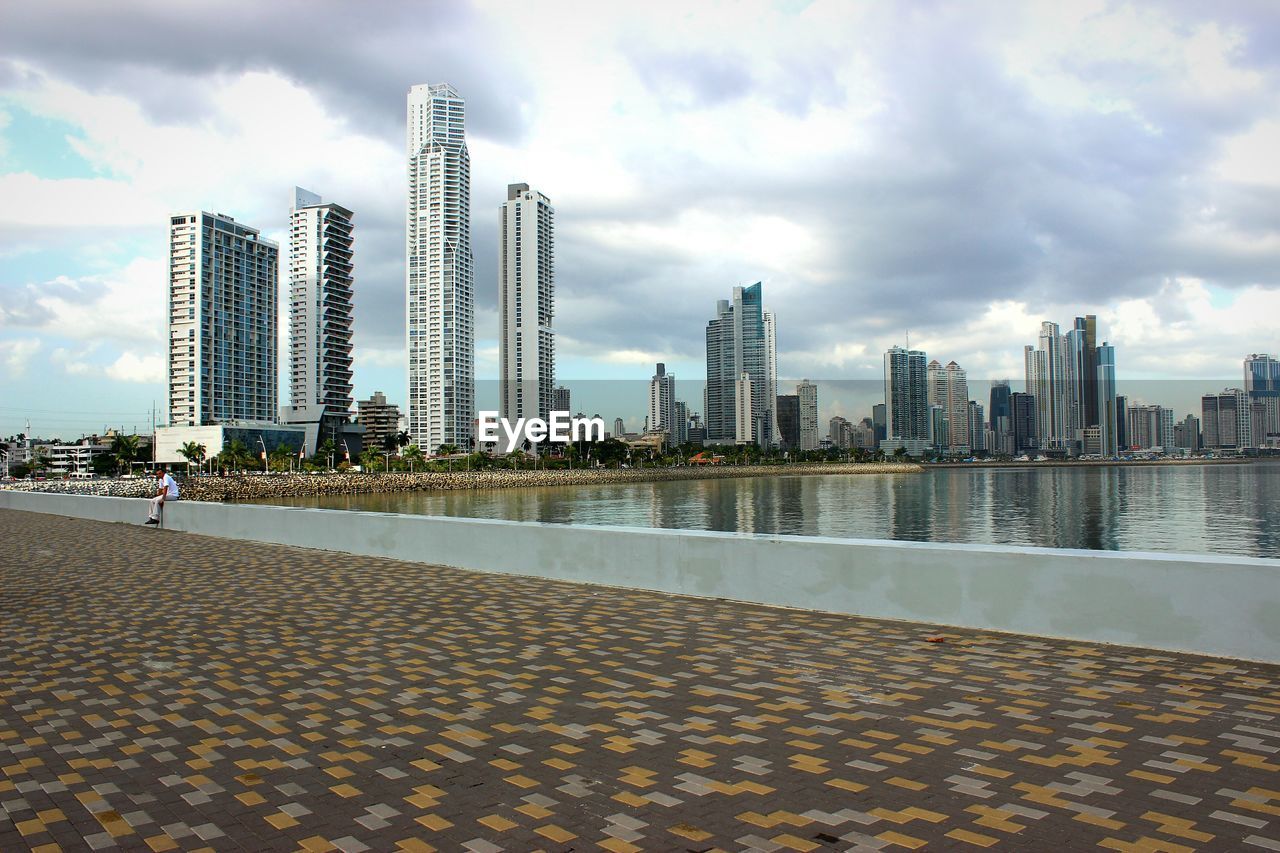 Promenade by lake against city