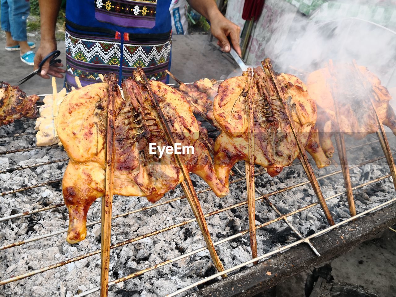 MIDSECTION OF MAN WITH MEAT ON BARBECUE