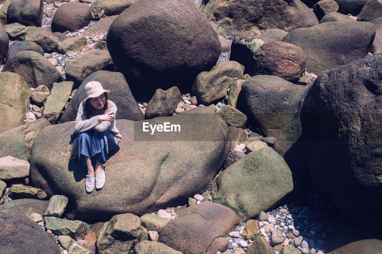 High angle view of woman sitting on rock at beach