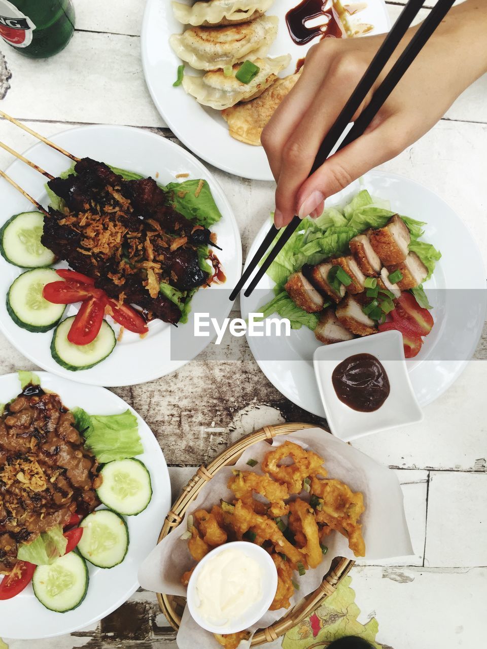 Cropped hand with chopsticks reaching towards food on plate