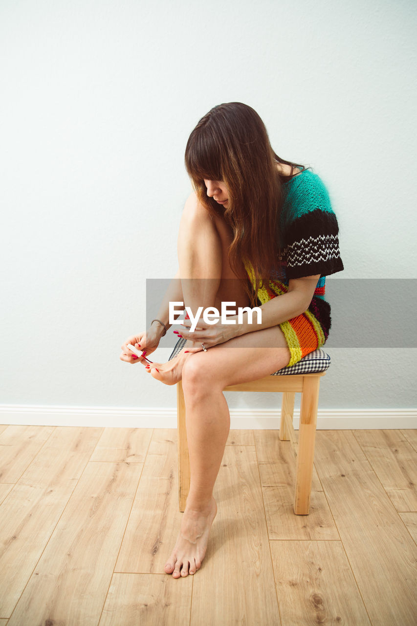 Woman painting toenails at home