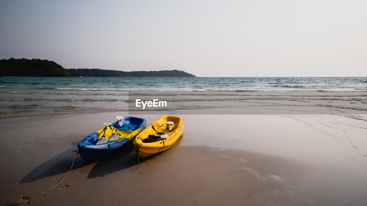 Boat moored on beach against clear sky