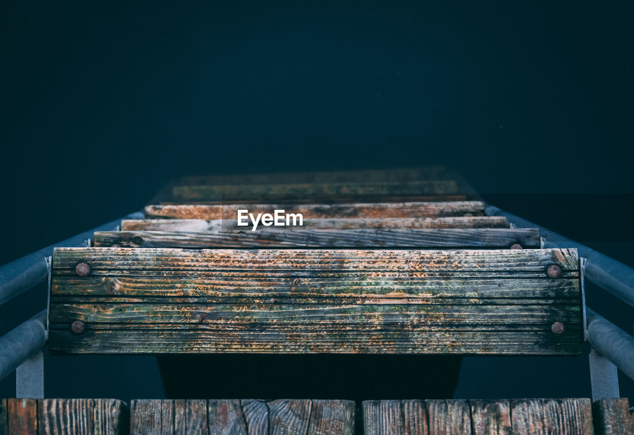 Close-up of wooden ladder on black background