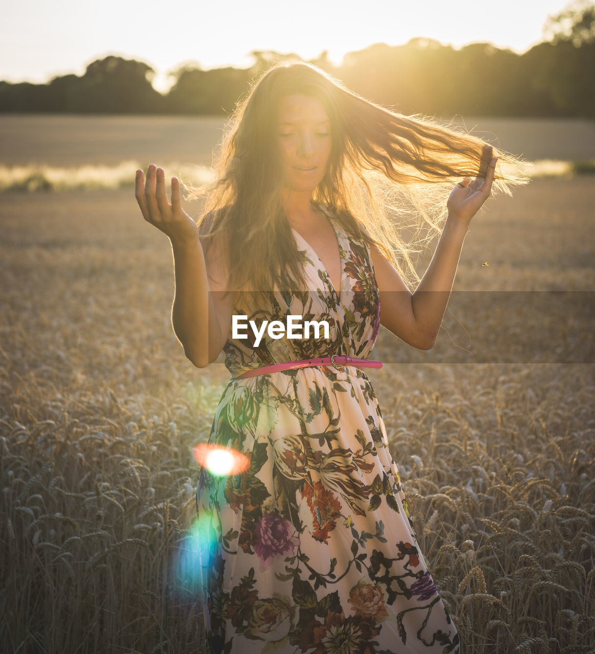 Mid adult woman wearing dress while standing on field at sunset