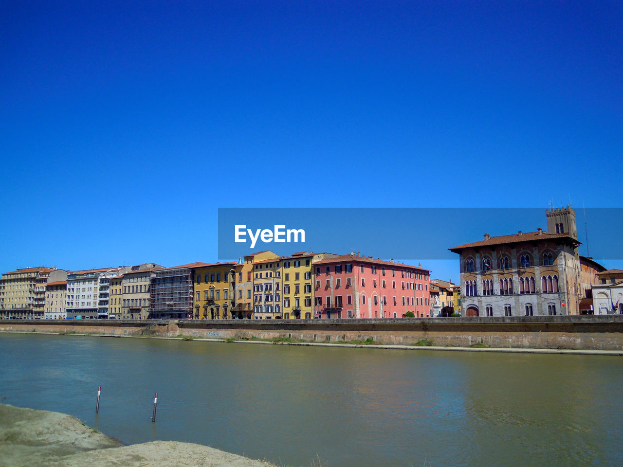 BUILDINGS BY RIVER AGAINST BLUE SKY