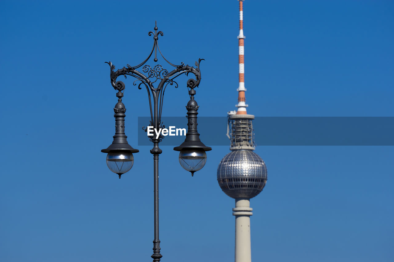 Low angle view of communications tower against sky in city