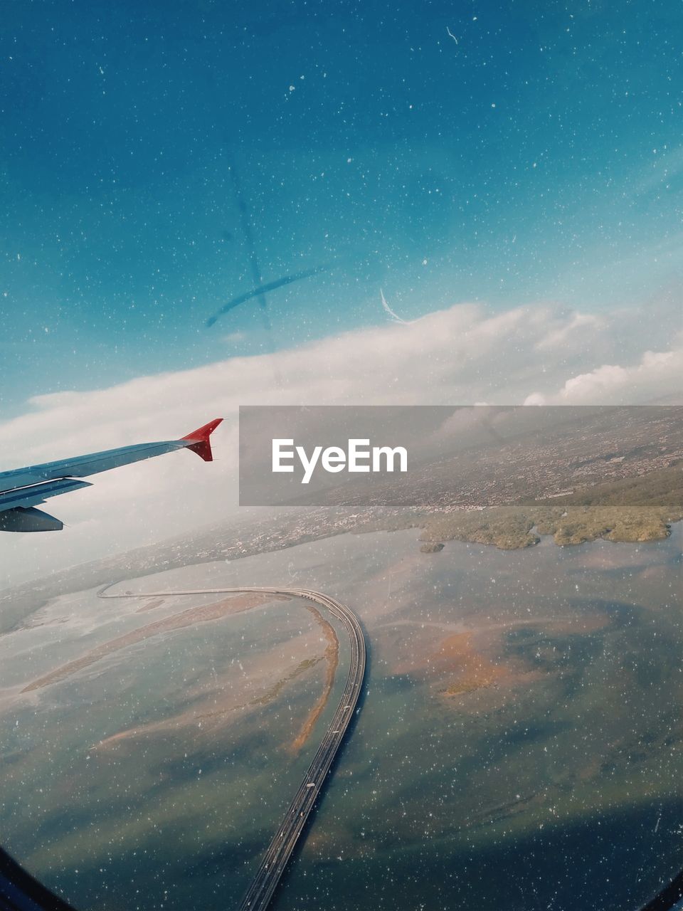 Airplane flying in sky seen through glass window
