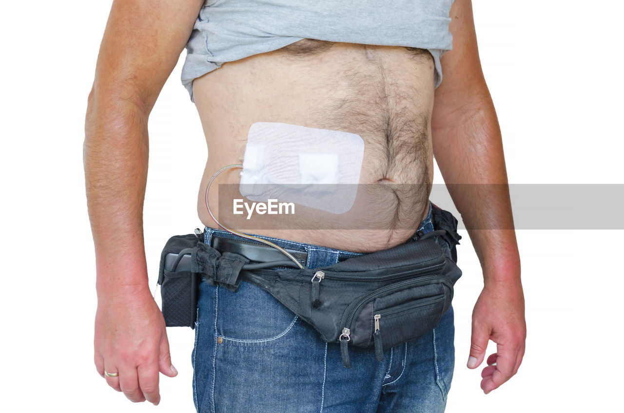 Midsection of man with bandage on abdomen against white background