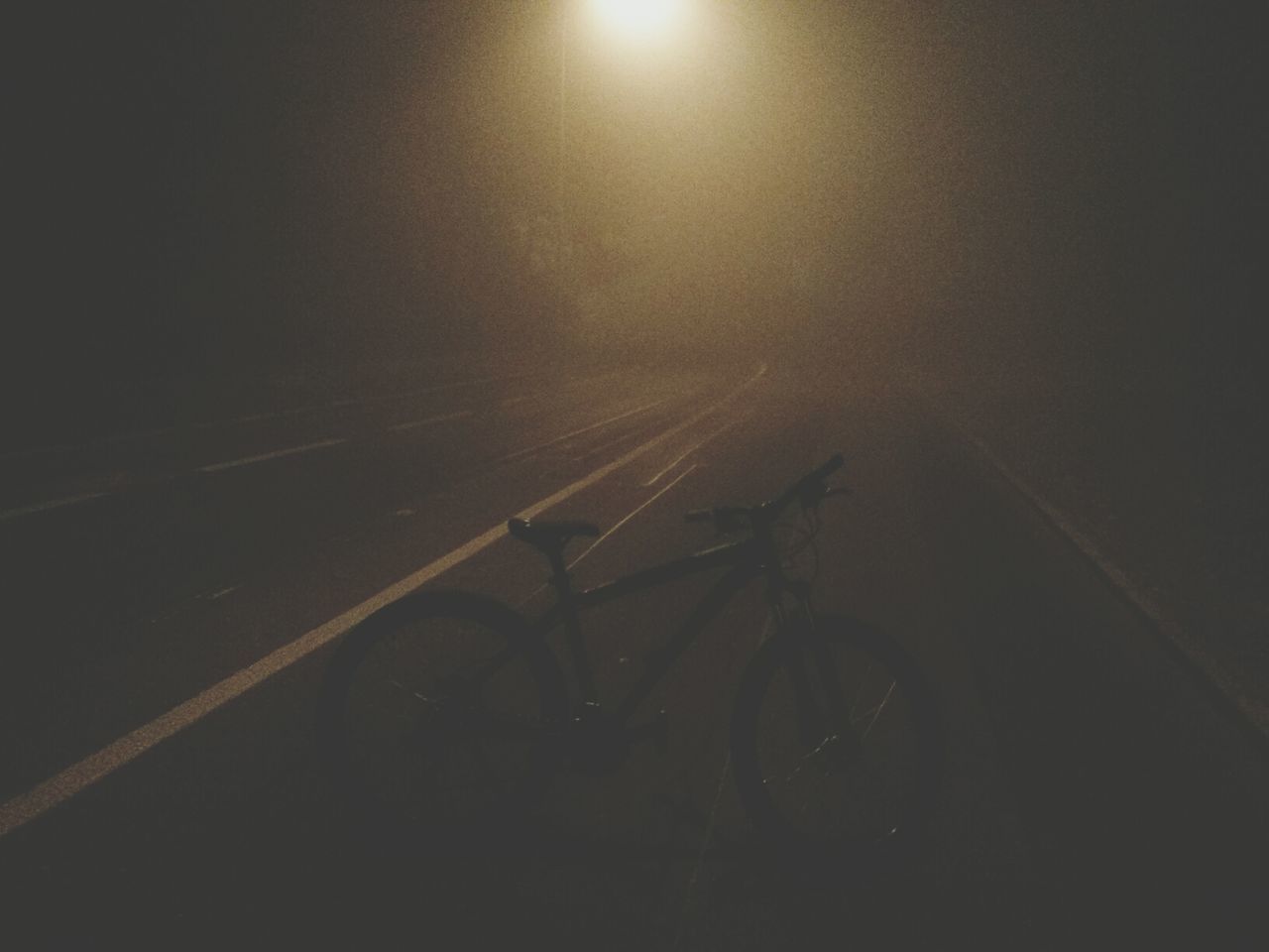 Bicycle parked in middle of road in fog at night