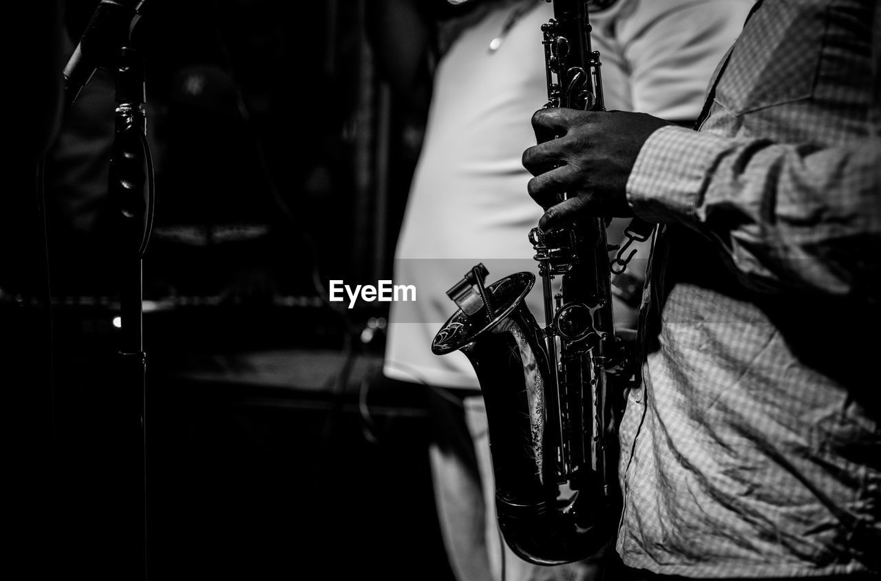 Midsection of male musician playing saxophone