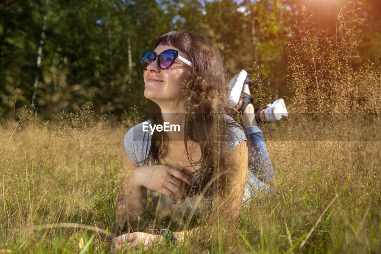 Beautiful young woman in sunglasses enjoys the sun on the grass person