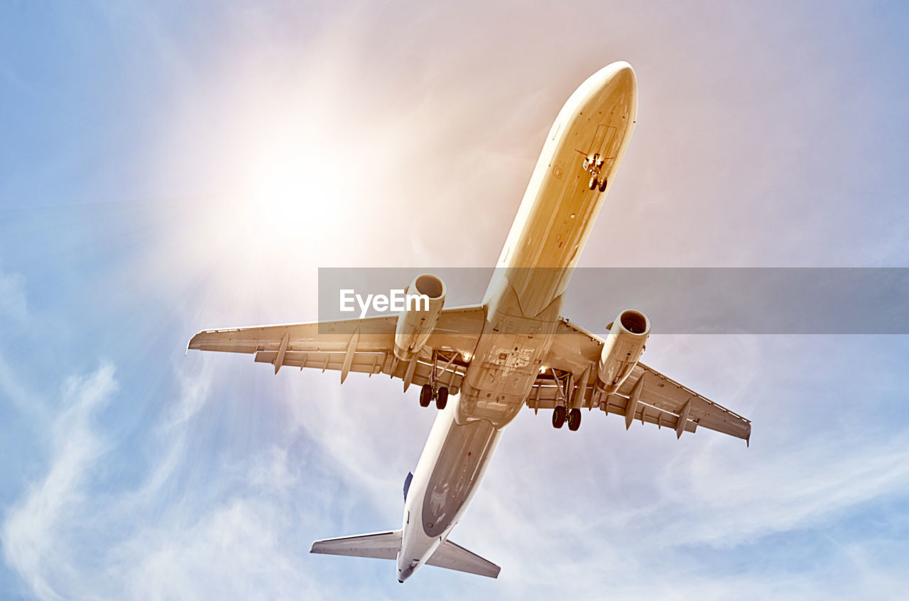 Low angle view of airplane flying against cloudy sky