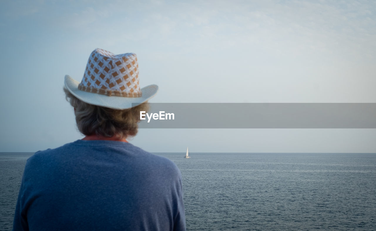 Rear view of man looking at sea against sky