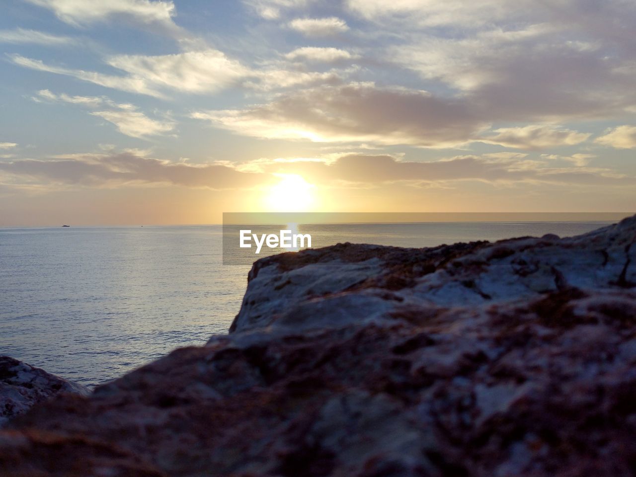 SCENIC VIEW OF ROCKY BEACH AGAINST SKY DURING SUNSET