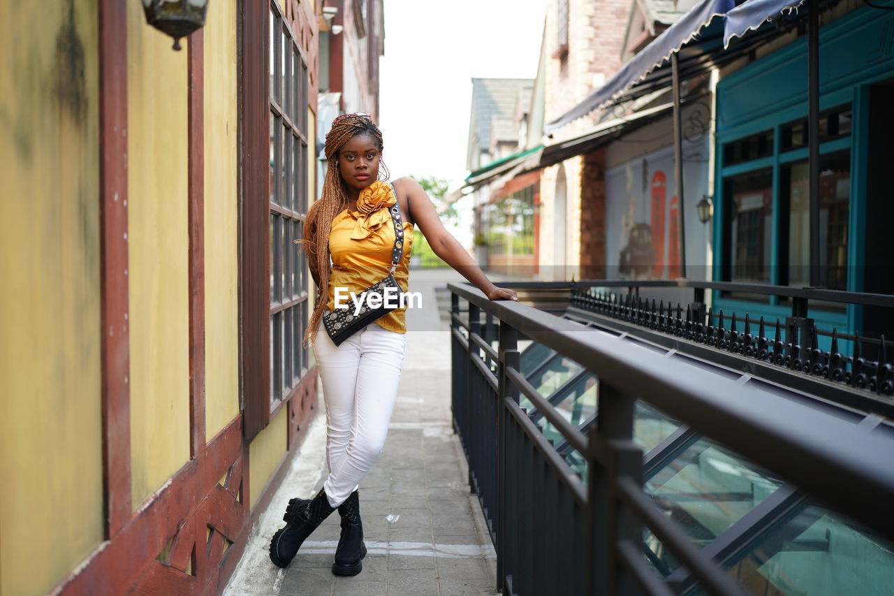 full length of young woman standing on footpath