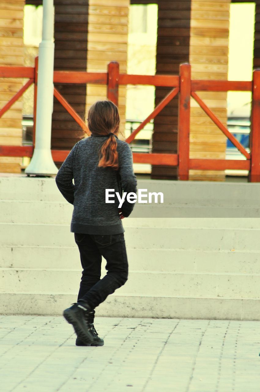 Rear view of woman walking on footpath