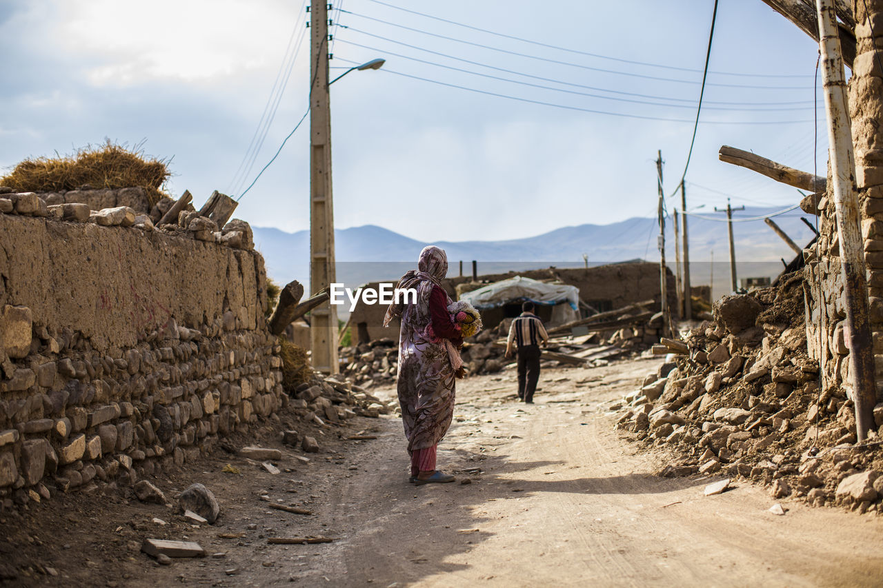 Rear view of woman standing on dirt road