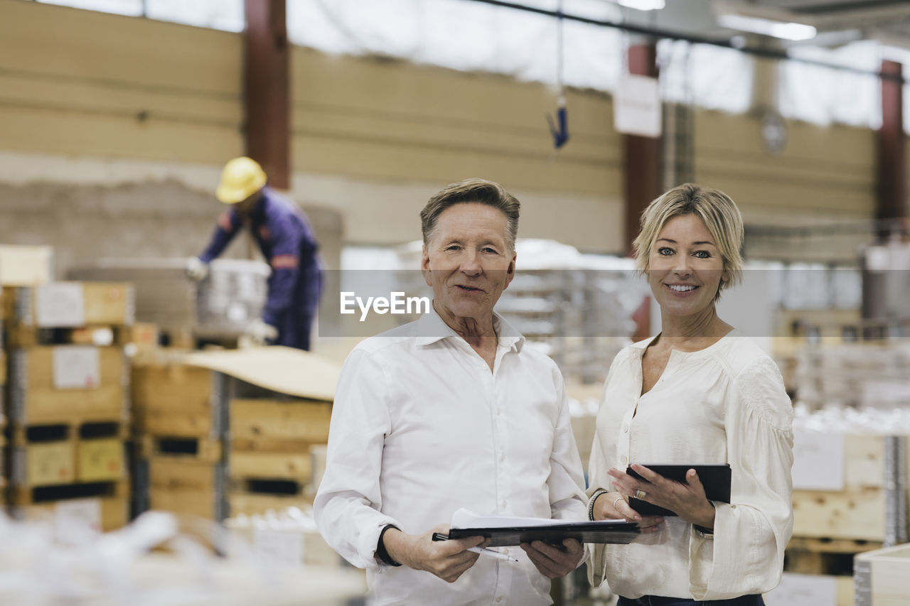 Portrait of senior businessman with daughter in factory warehouse