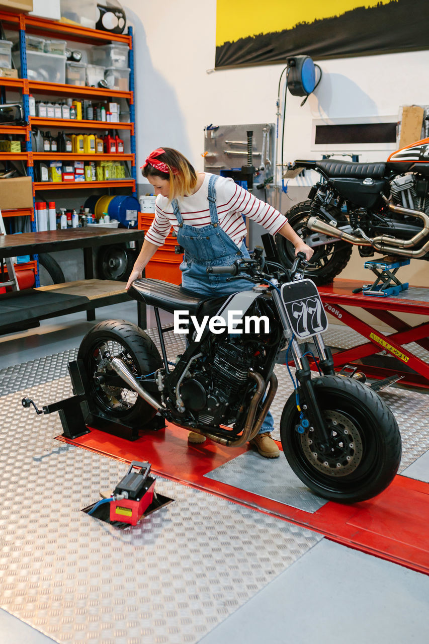 Mechanic woman placing custom motorcycle over platform